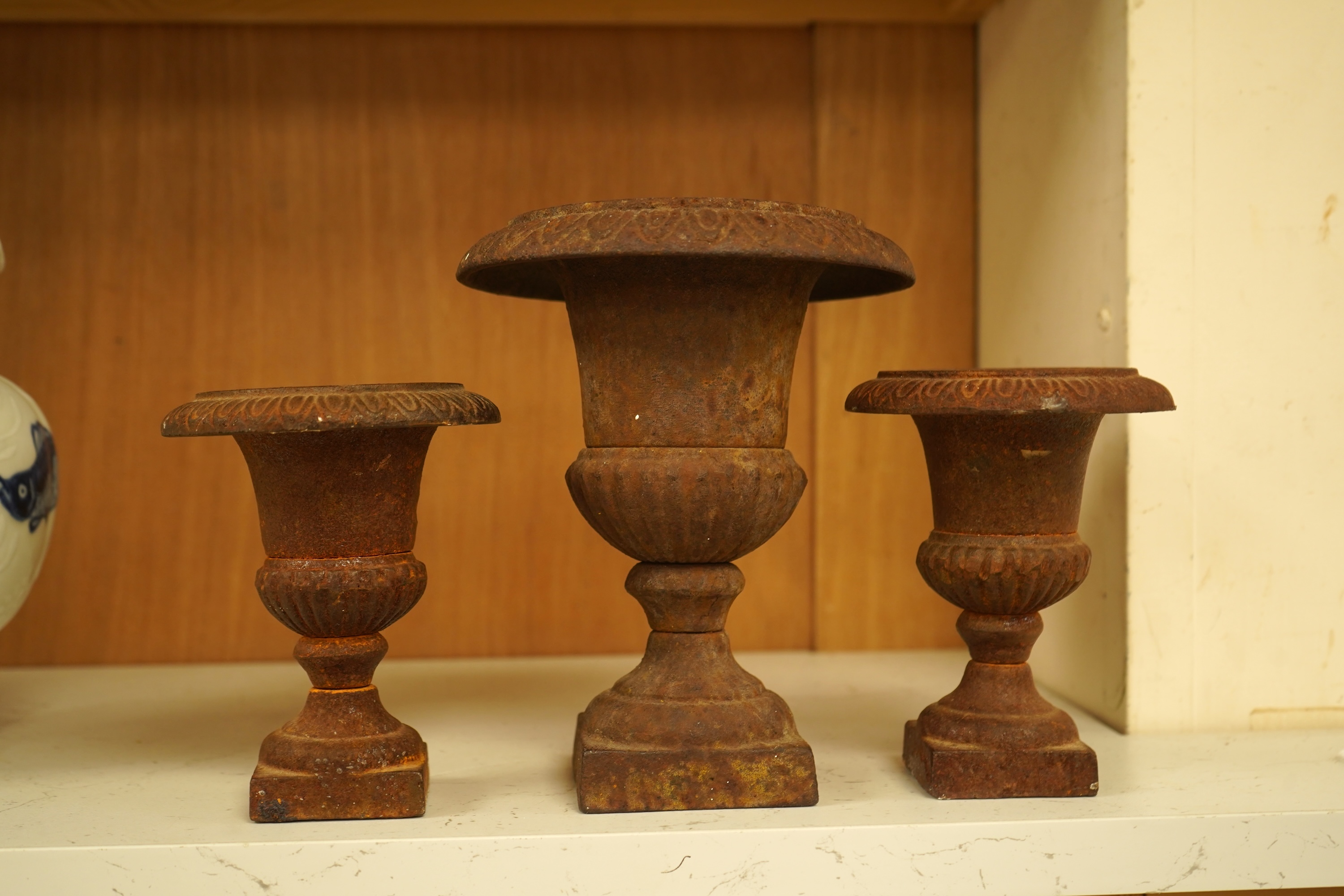A garniture of three cast iron campana vases, largest 18cm high
